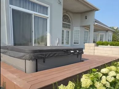 Modern house patio with a covered hot tub and wooden decking.