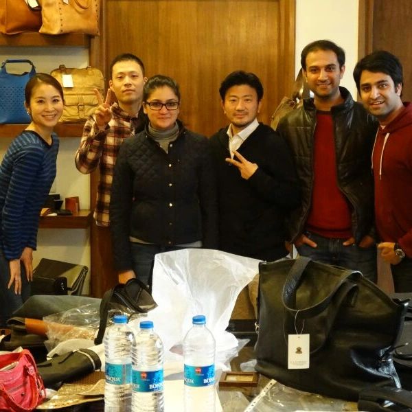 Group of six people posing happily in a store with bags and water bottles on the table.