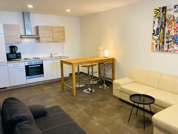 Modern kitchen and living room with neutral tones and minimalist furniture.