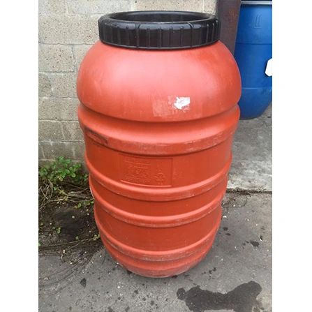 Large orange plastic barrel with black lid outdoors.