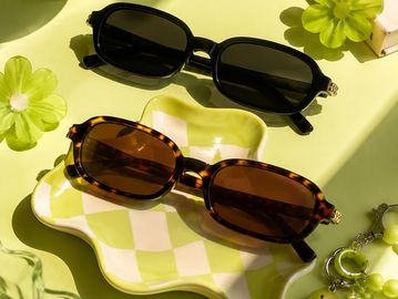 Two pairs of stylish sunglasses on a patterned tray.