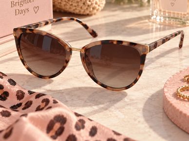 Trendy tortoiseshell sunglasses on a marble surface.