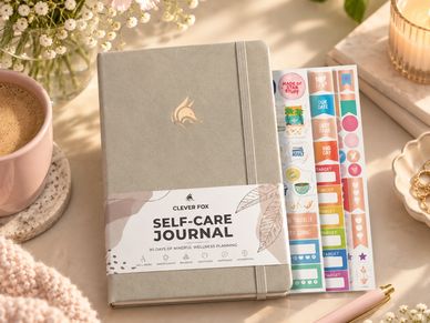 Self-care journal with stickers on a cozy desk.