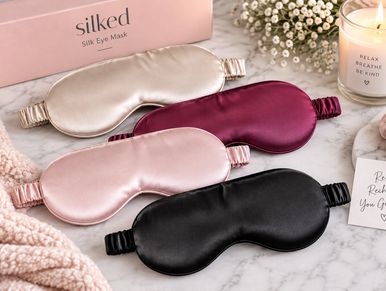 Four silk eye masks in various colors on a marble surface.