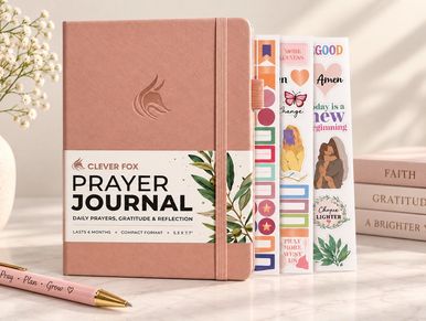 A pink Clever Fox Prayer Journal with bookmarks and a pen.