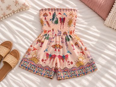 Floral and sun patterned strapless romper laid out on a bed.