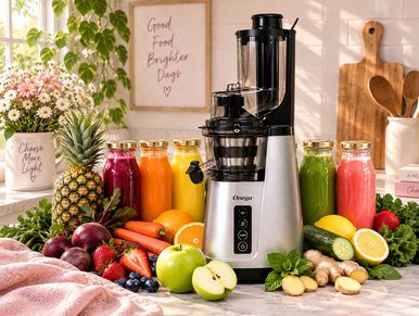 Juicer surrounded by fresh fruits and vegetables on a kitchen counter.