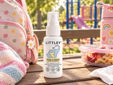 Baby hand sanitizer on picnic table with toys and snacks.