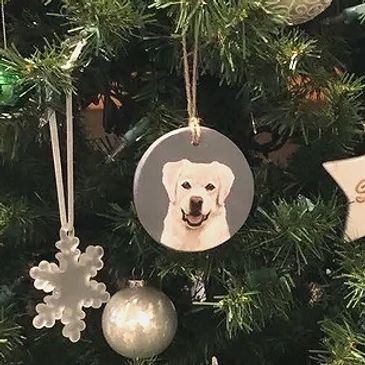 Clay ornament with a painted white Golden Retriever dog portrait, hanging on a Christmas tree