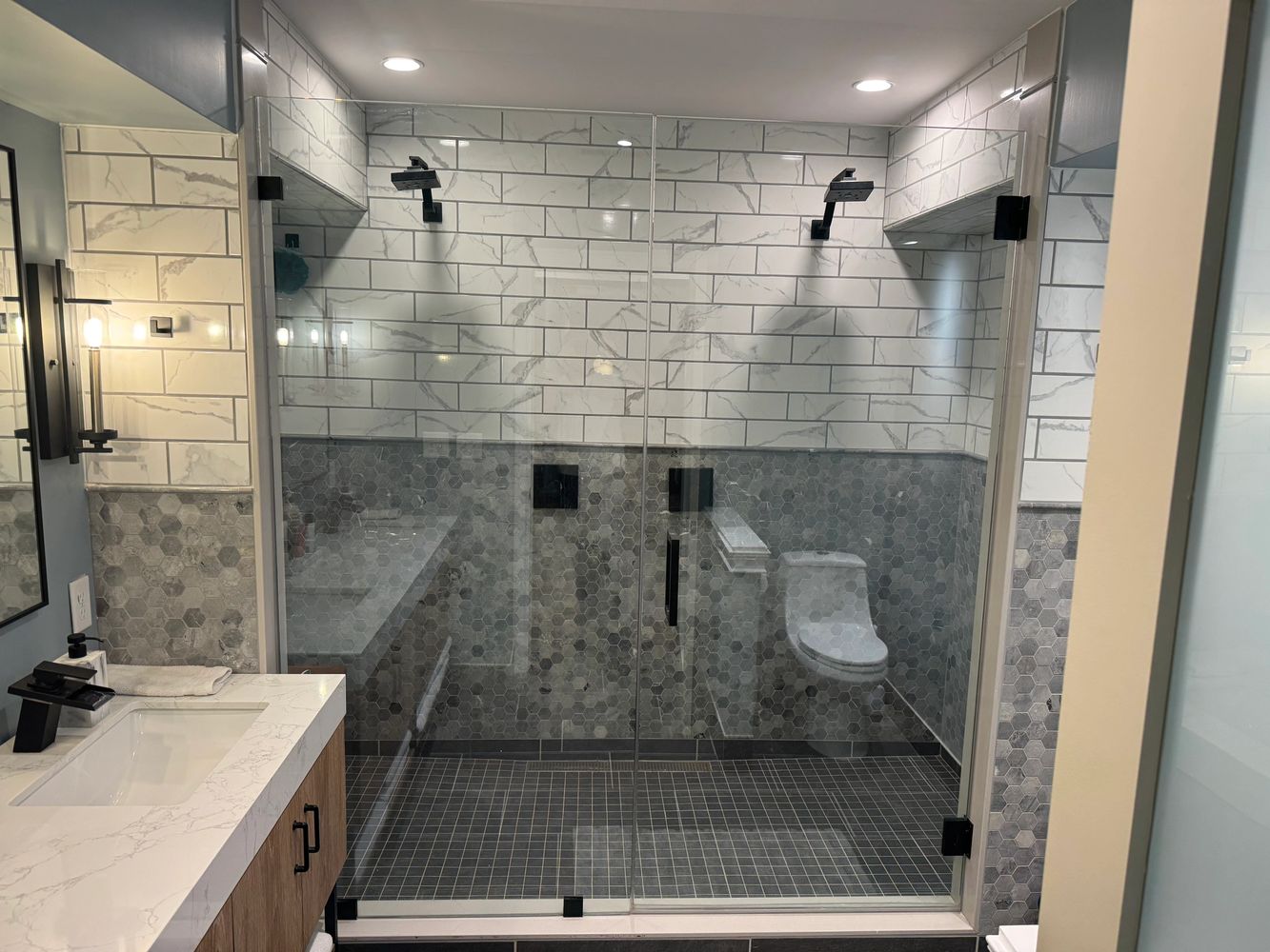 Modern bathroom with glass shower and marble tiles.