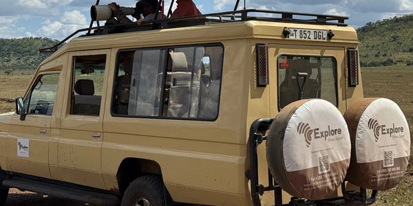 Safari vehicle with tourists viewing wildlife under a partly cloudy sky.