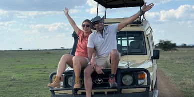 Two people sitting on a safari vehicle, enjoying the outdoors.