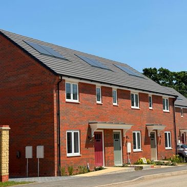 Row of modern brick townhouses with solar panels on the roof.