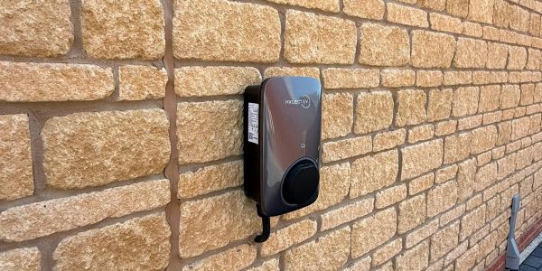 Electric vehicle charger mounted on a brick wall.