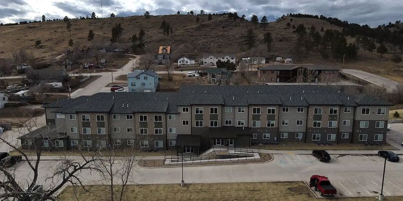 An exterior image of Discovery Village, a large apartment complex in muted shades of green. 