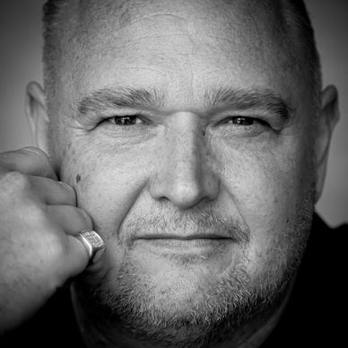 Close-up black and white portrait of a man with a contemplative expression.