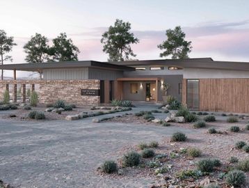Modern desert home with flat roof and natural landscaping.