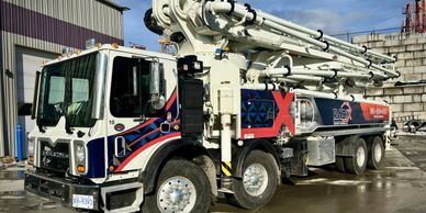 A large concrete pump truck parked outdoors on a sunny day.