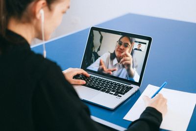 Person having a video call and taking notes.