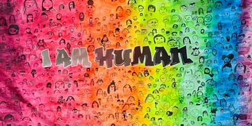 Colorful mural with diverse faces and bold text saying 'I AM HUMAN'.