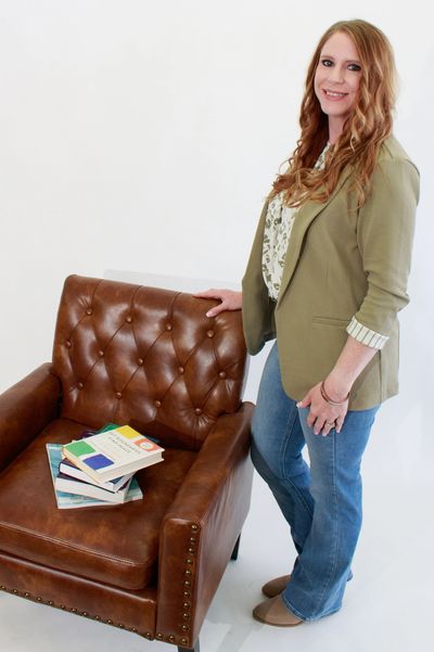 business professional standing next to a chair with a stack of books