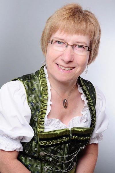 Portraitfoto Heidi Stuffer im festlichen grünen Dirndl mit weißer Bluse und einem Medaillon