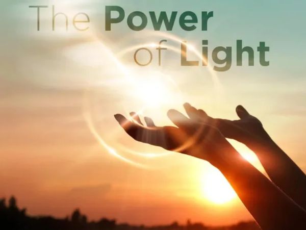 Hands reaching towards a glowing light at sunset with the text 'The Power of Light'.