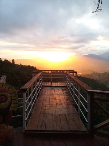 Wooden observation deck overlooking a scenic sunset over mountains.