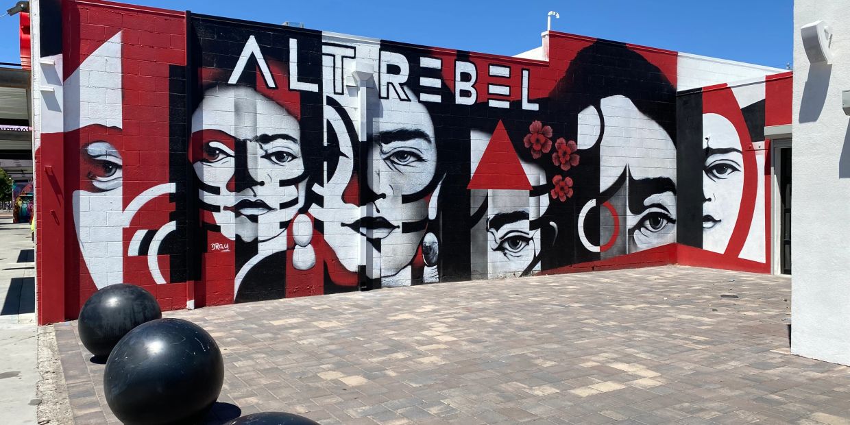 A bold mural featuring stylized black, white, and red portraits with the text 'ALTREBEL'.
