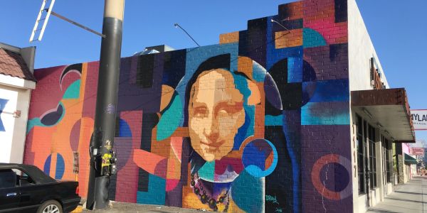 Colorful geometric mural with Mona Lisa's face on a building wall.