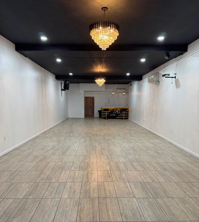 Spacious modern room with chandelier lighting and a reception desk.