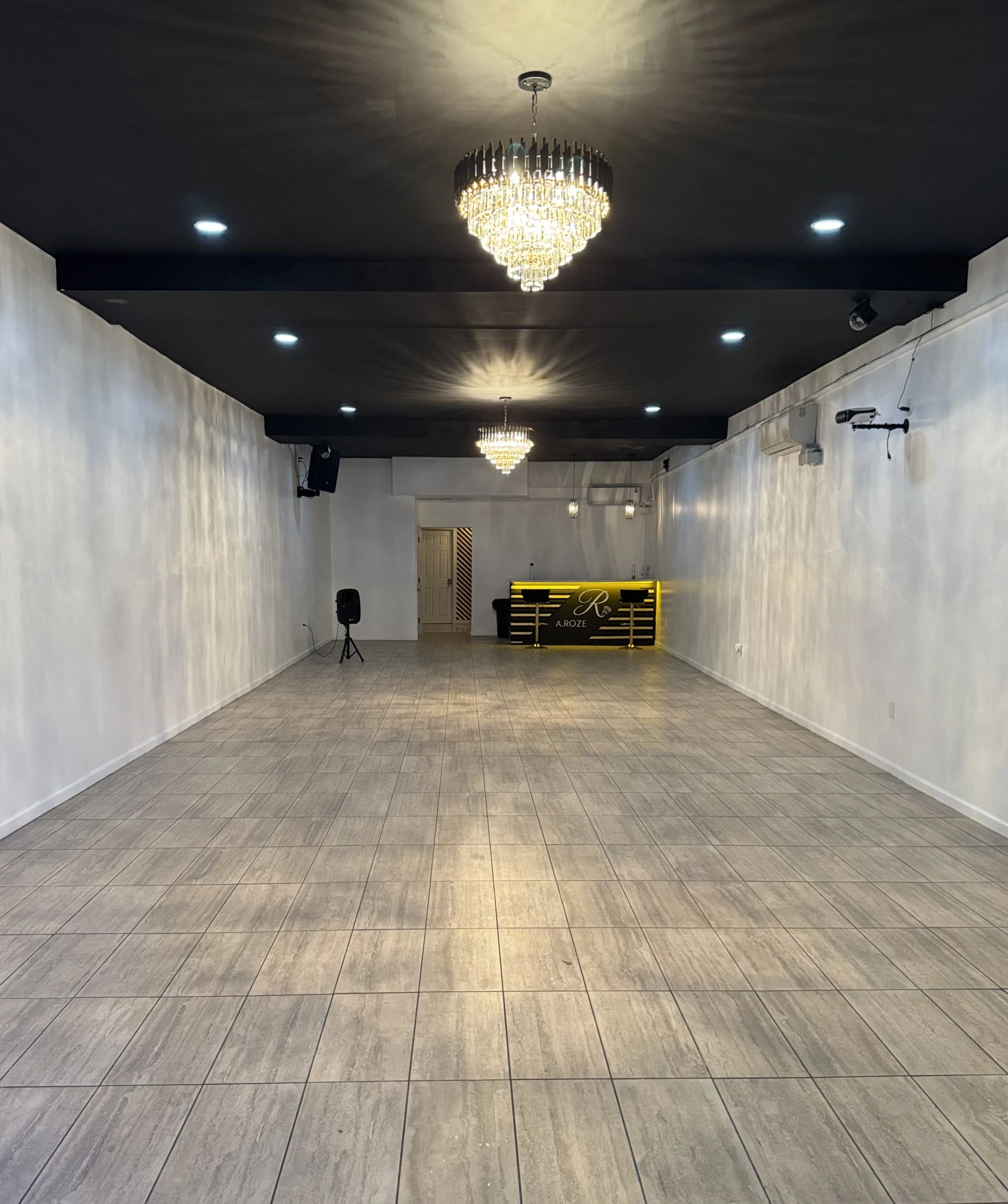 Modern empty room with chandeliers and tiled floor.