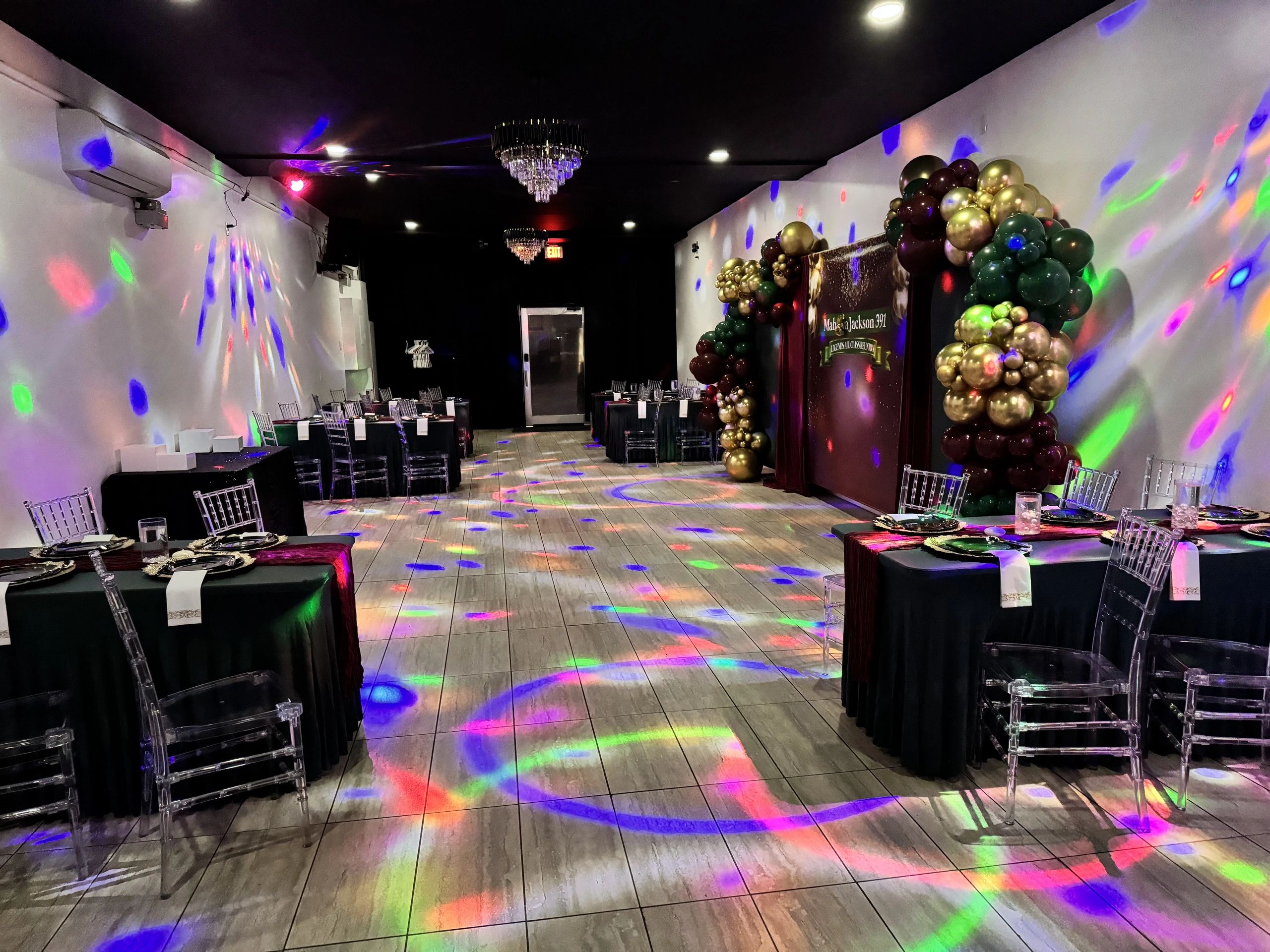 Decorated event hall with colorful lights and balloon arrangements.