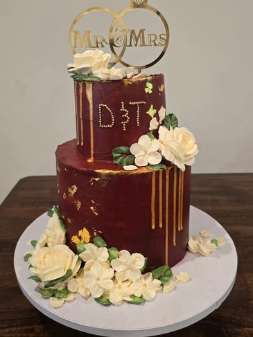 Elegant two-tier wedding cake with maroon icing and white floral decorations.