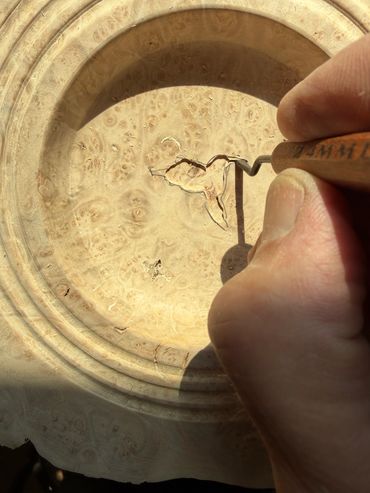 Hand carving a design on a wooden surface.