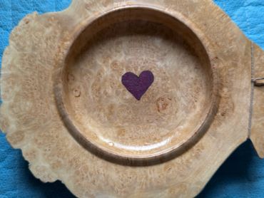 Wooden plate with a heart design in the center.
