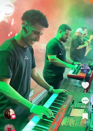Musicians playing keyboards and brass instruments on stage.