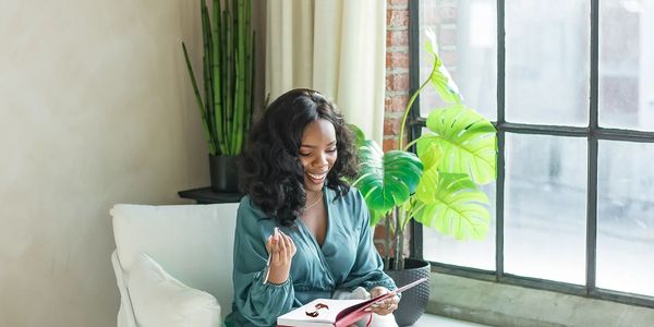 A woman sitting on a chair taking notes during their client's session.