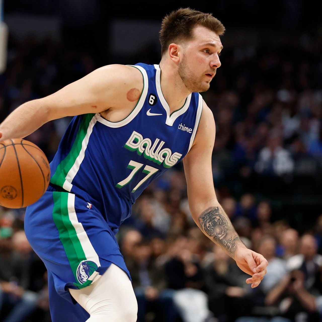 Luka Doncic dribbling a basketball while wearing a blue Dallas Mavericks jersey during a game.