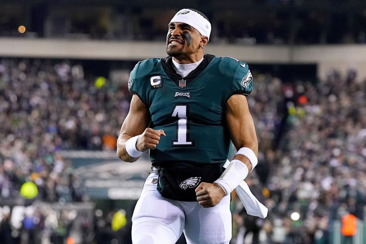 Philadelphia Eagles quarterback celebrating after a successful play, wearing a green jersey and headband.