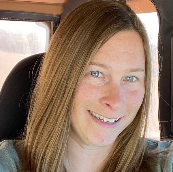 Smiling woman with long light brown hair inside a vehicle.