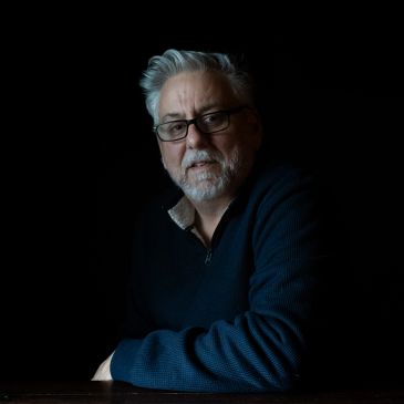 Portrait of a thoughtful man with glasses and gray hair.