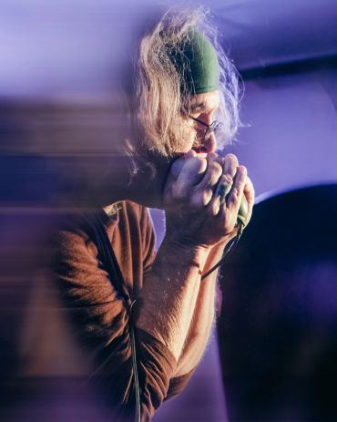 Person deeply focused while playing harmonica.