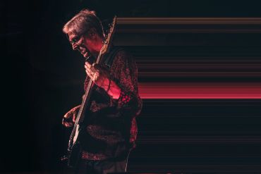 Man playing electric guitar on stage.