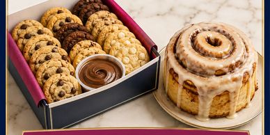 Assorted cookies and a cinnamon roll with icing.