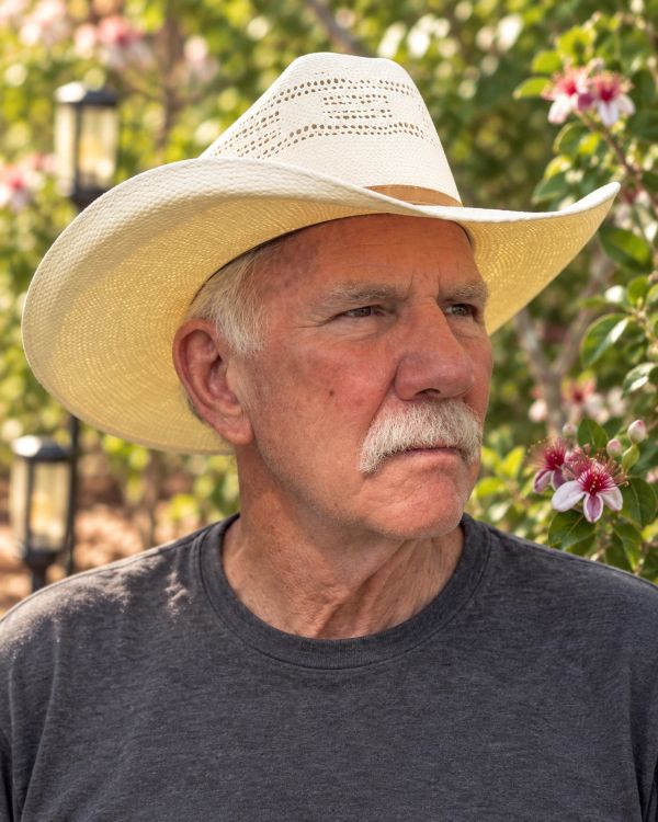 Portrait of Ol’ Jer in his white cowboy hat with Pineapple Guava blossoms behind him.