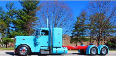 A classic blue semi-truck parked outdoors on a sunny day.