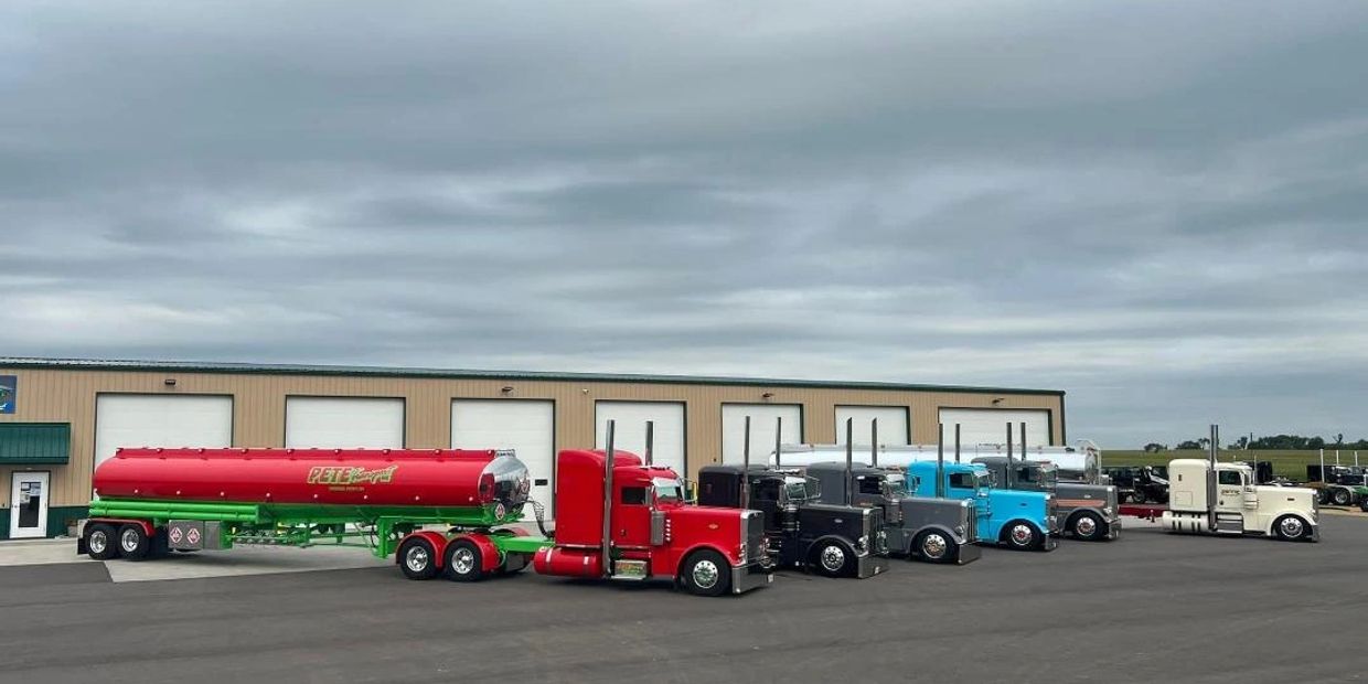 A lineup of colorful semi trucks parked in front of a warehouse.