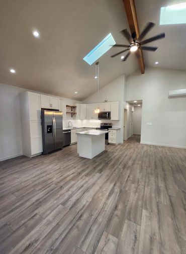 Modern kitchen with vaulted ceiling, skylights, and wood flooring.