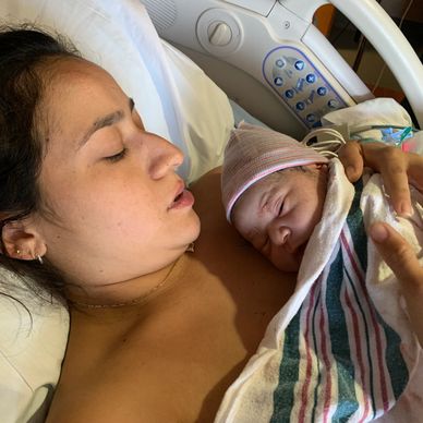 Mother holding newborn baby in hospital bed after a natural birth (VBAC)